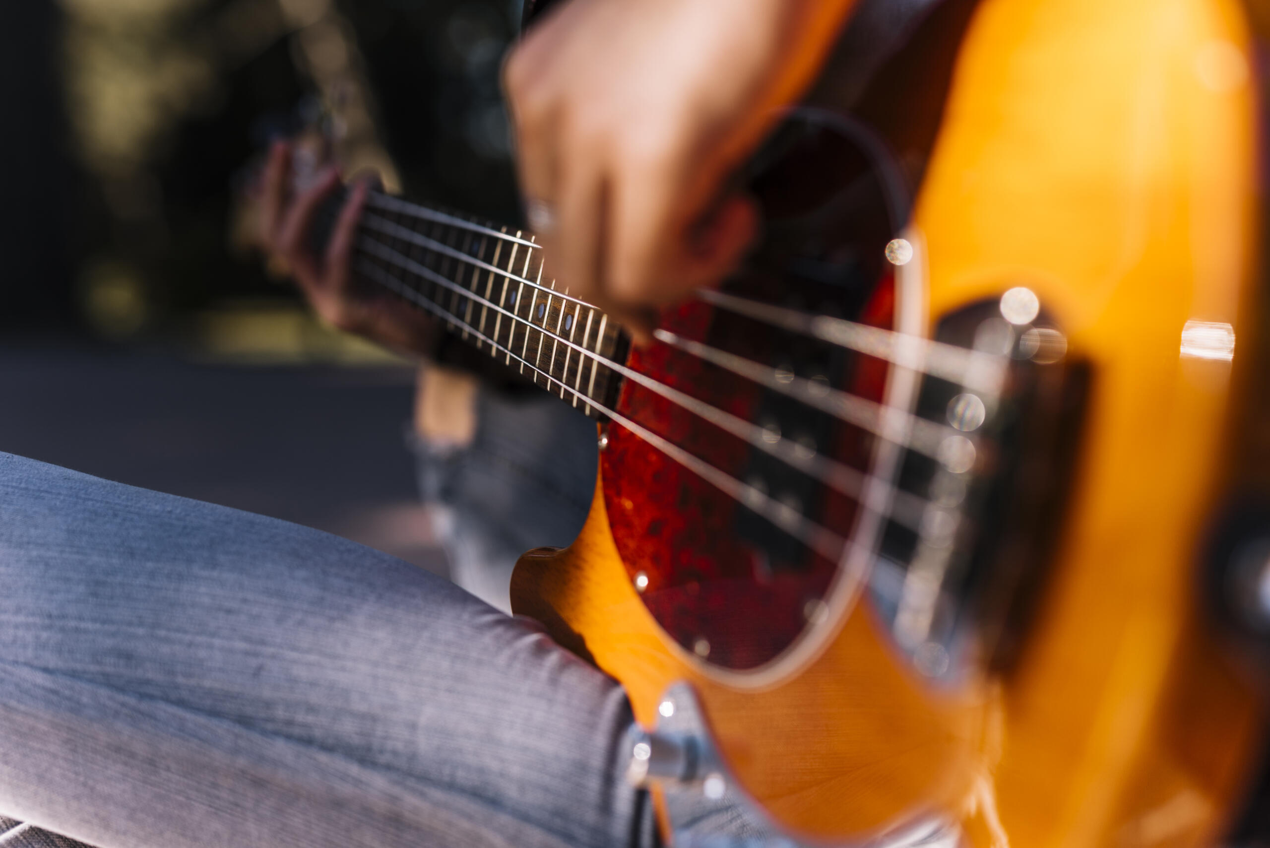 toma detalle de una guitarra en primer plano de lado con unas manos tocando