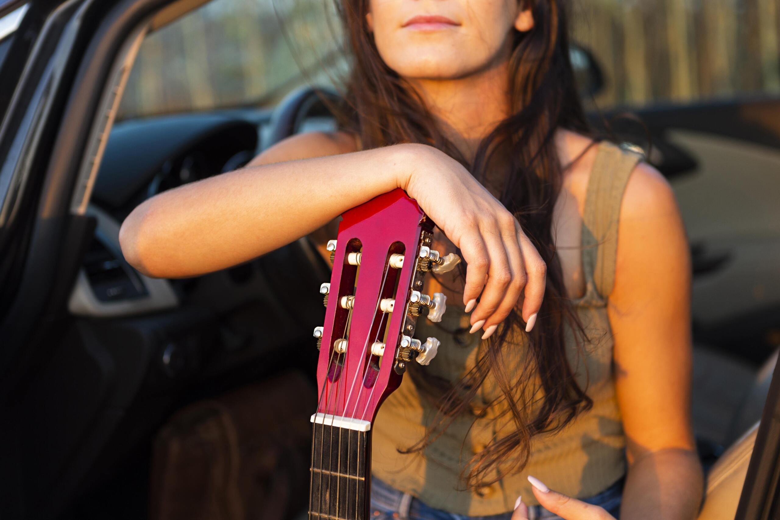 vista detalle de chica con la mano y mentón apoyados en la pala de la guitarra