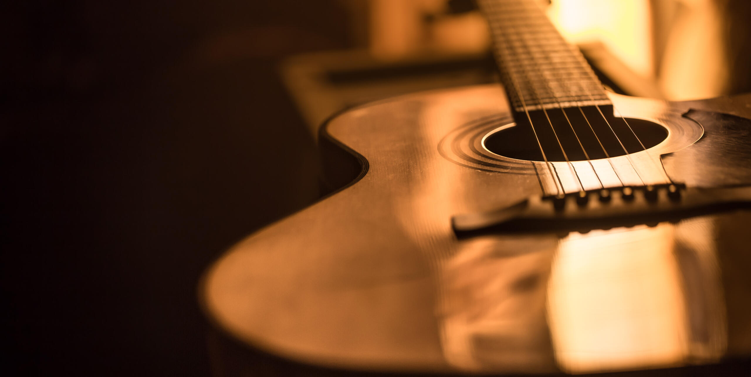vita detalle de una guitarra echada entre sombras