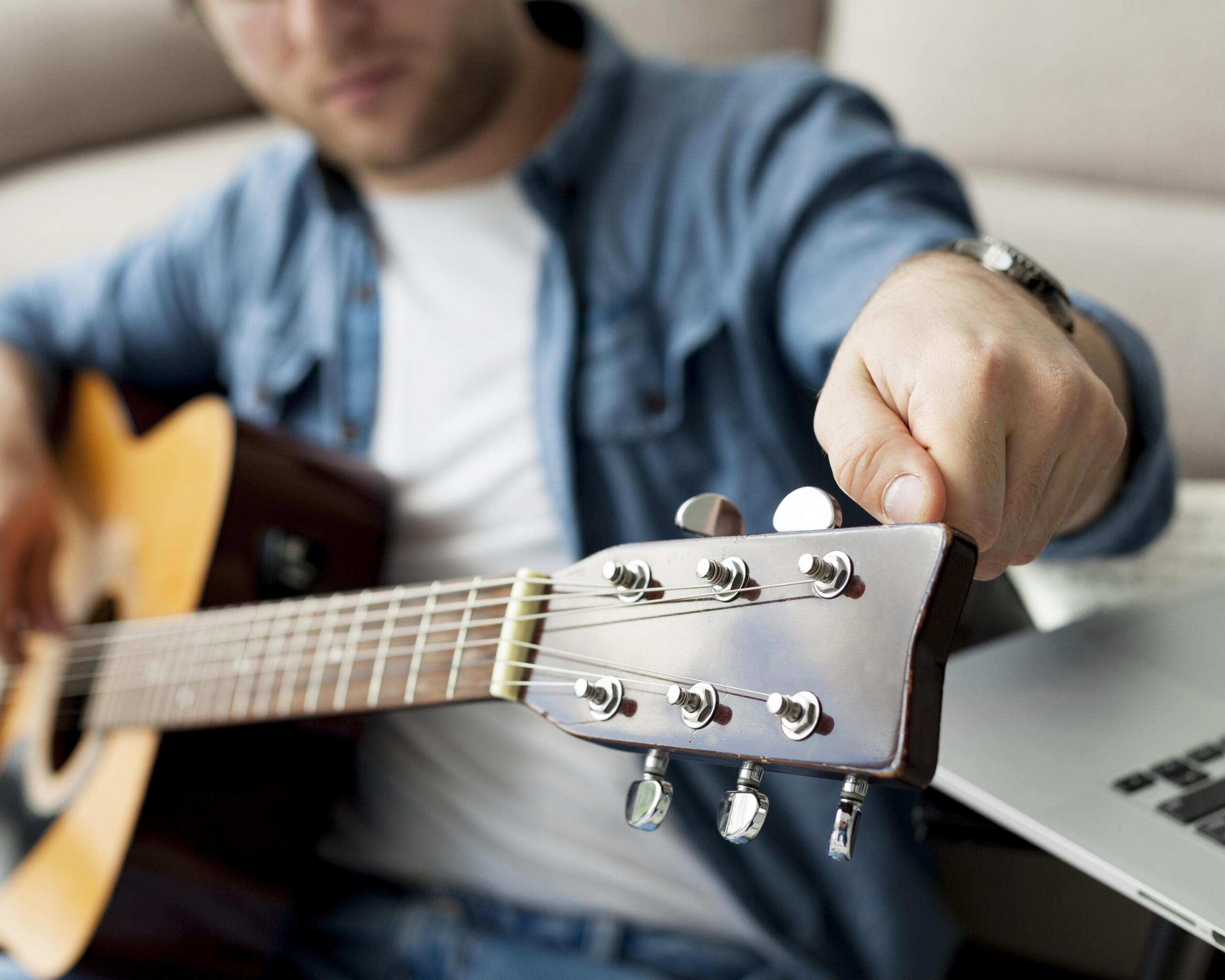primer plano de mano afinando las cuerdas de la guitarra 