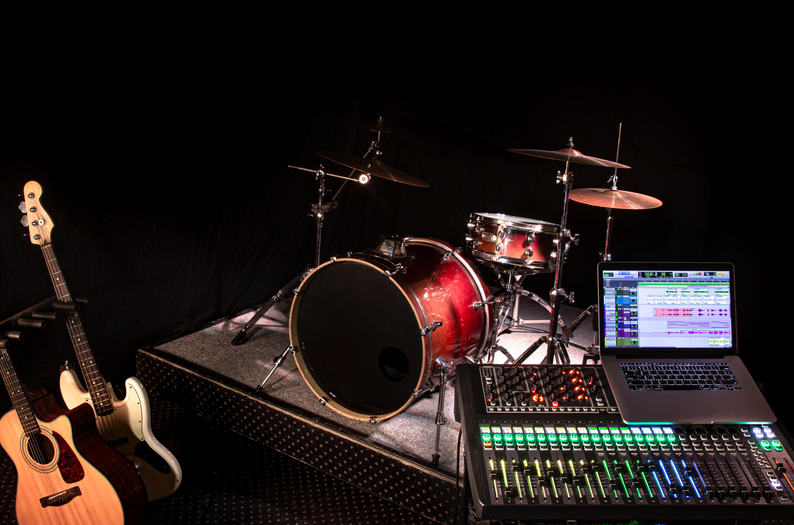 vista de bateria, guitarras y modulares de audio en un estudio de fondo oscuro.
