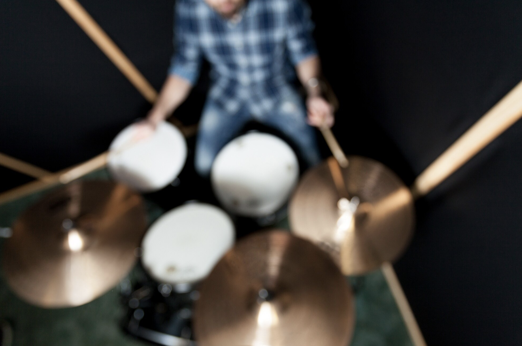 vista contrapicada desefocada de un baterista tocando los platillos con las baquetas