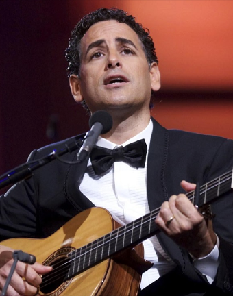 Retrato de Juan Diego Florez en escenario con guitarra en mano