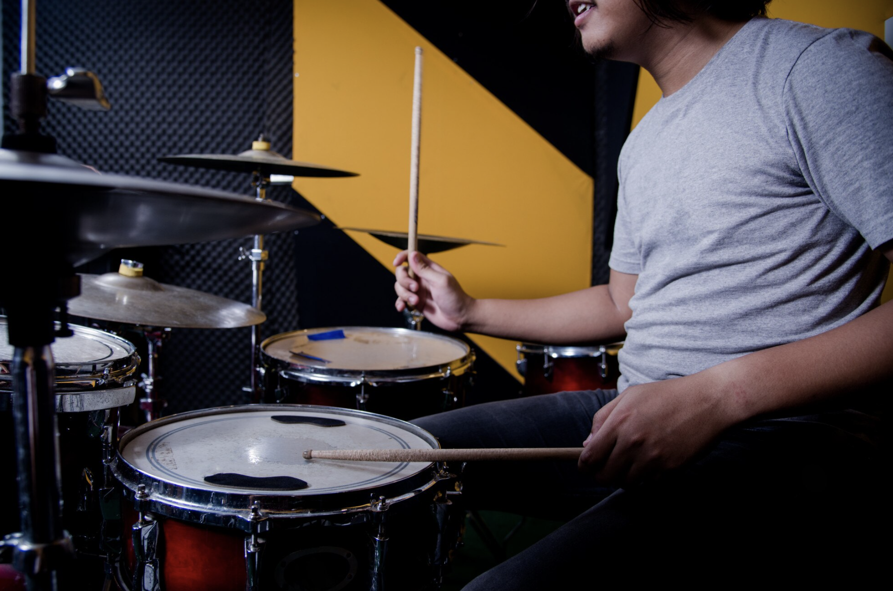 vista de lado de un chico tocando la batería en un estudio salón