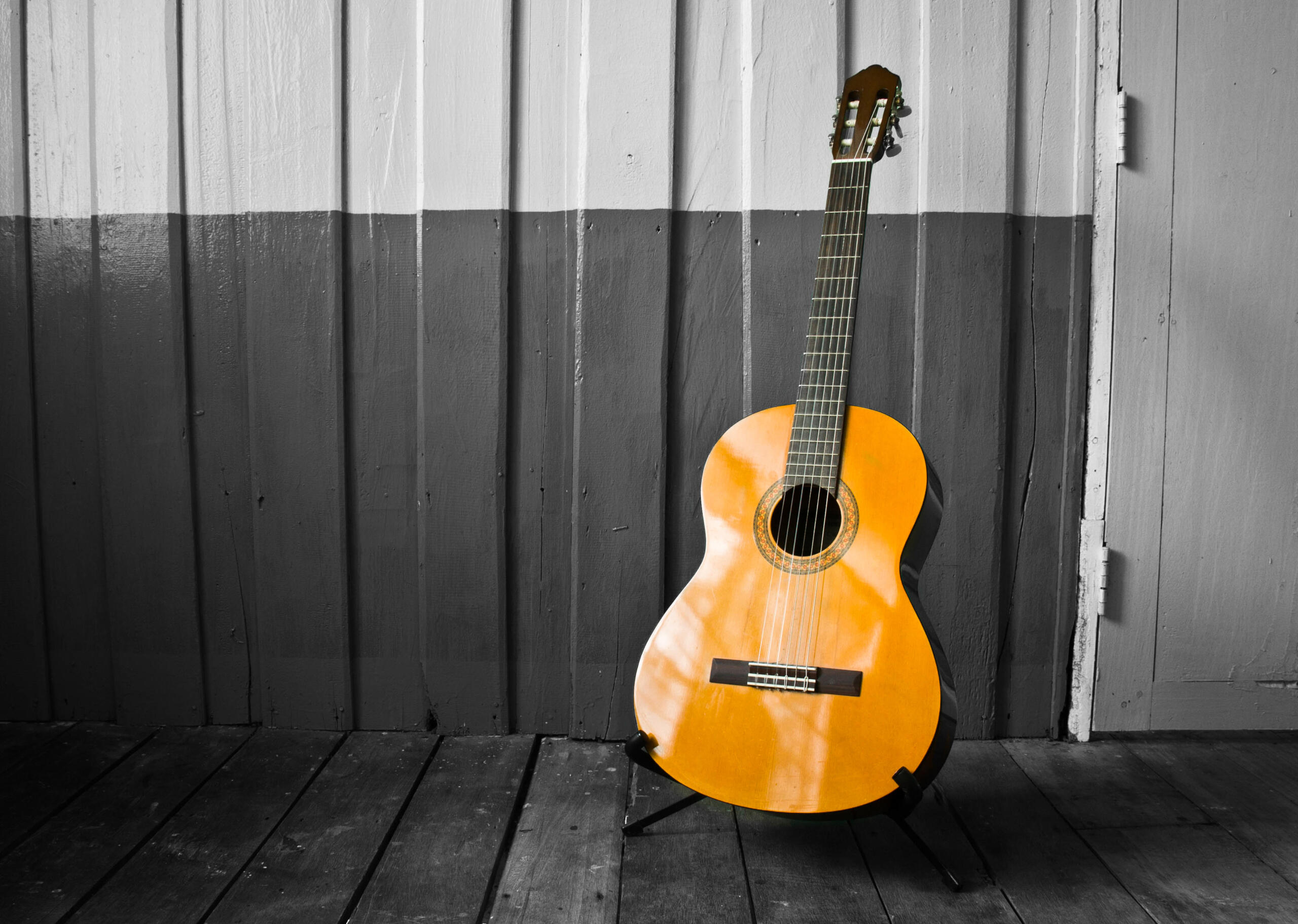 guitarra acústica amarilla resaltando de un fondo a blanco y negro