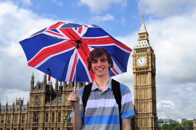 chico feliz con un paraguas de la bandera de londres con el Big ben de fondo