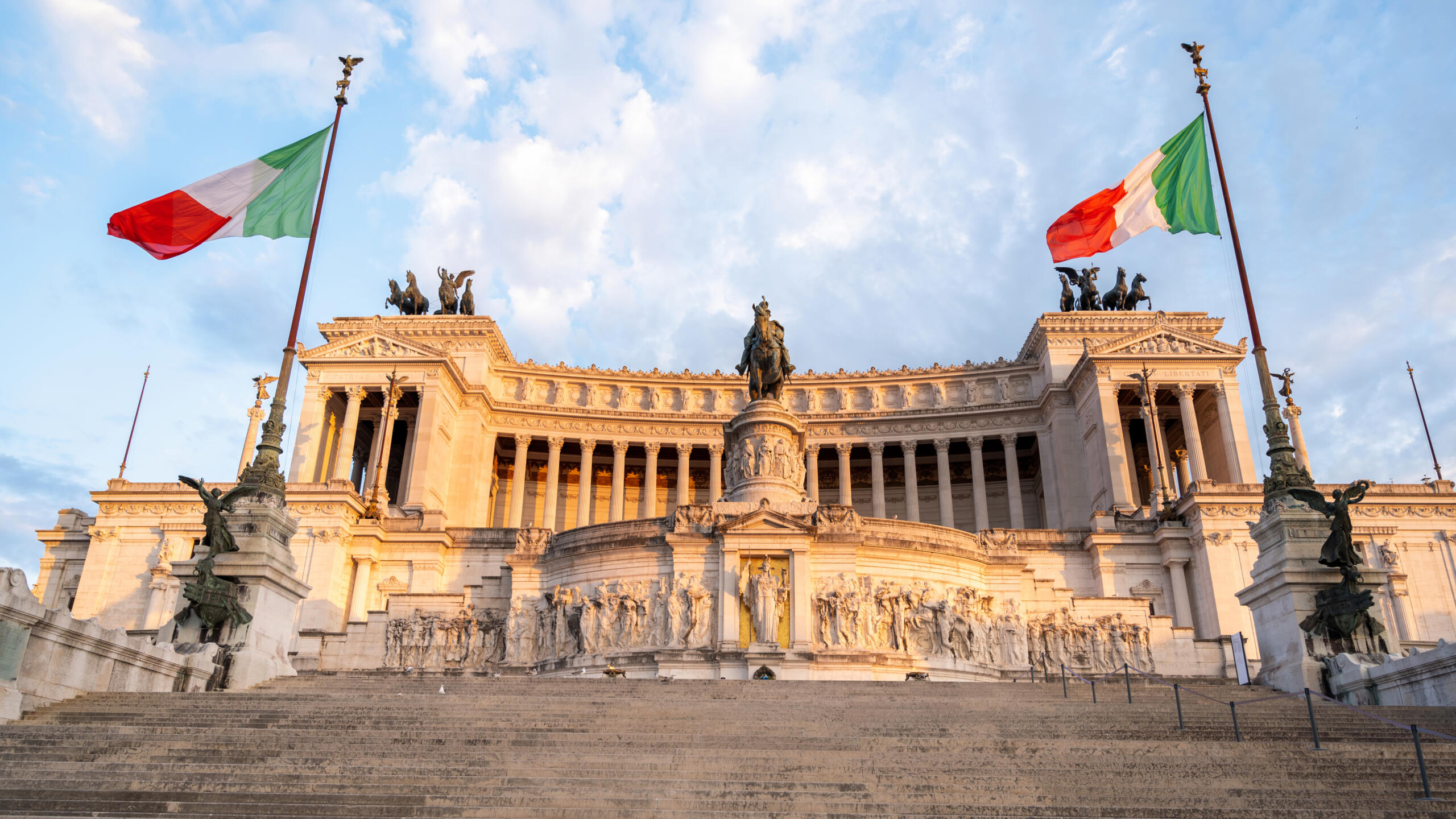 toma abierta del monumento Victor Emmanuel II de Roma junto a dos banderas italianas