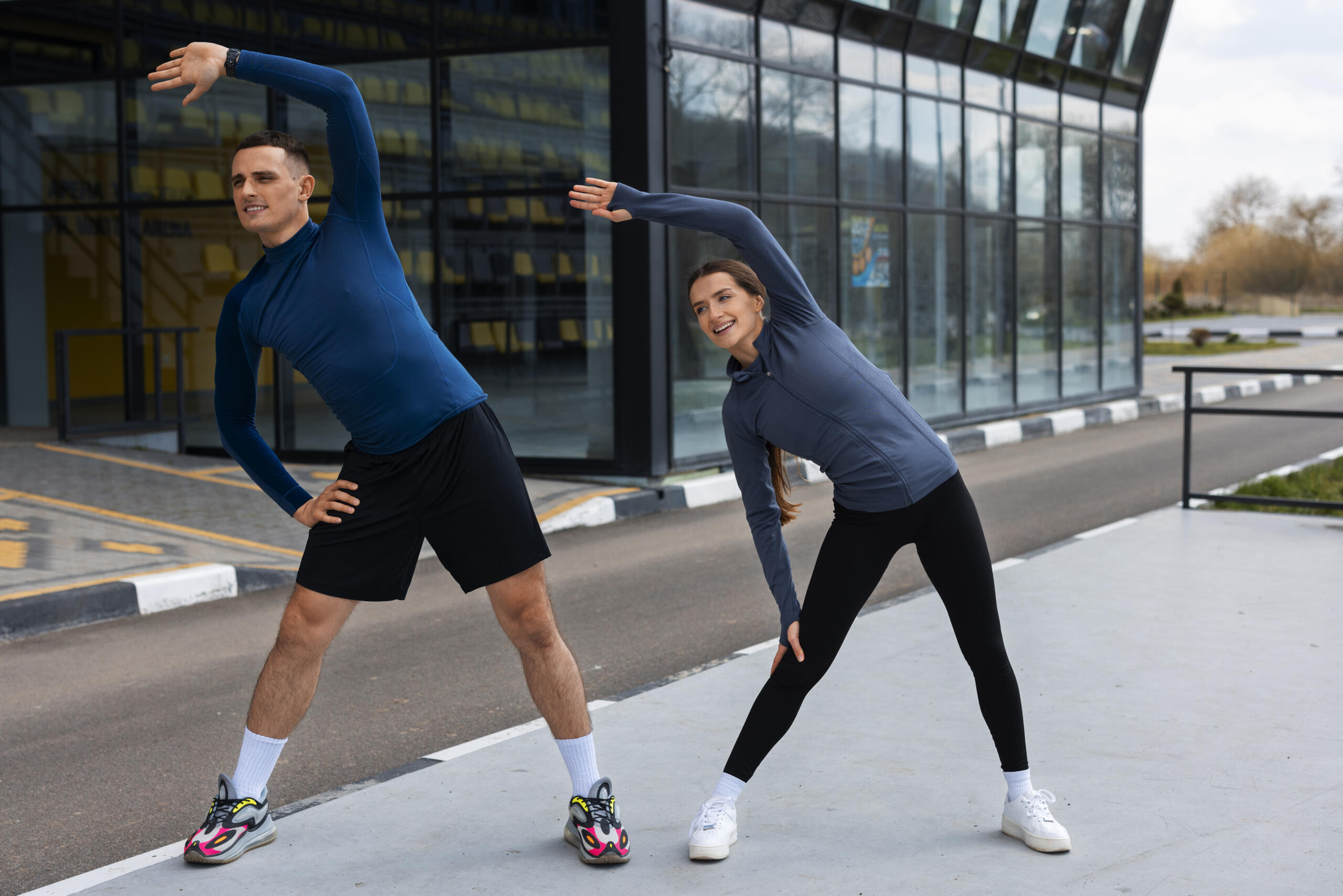 chico y chica haciendo estiramientos laterales en la calle