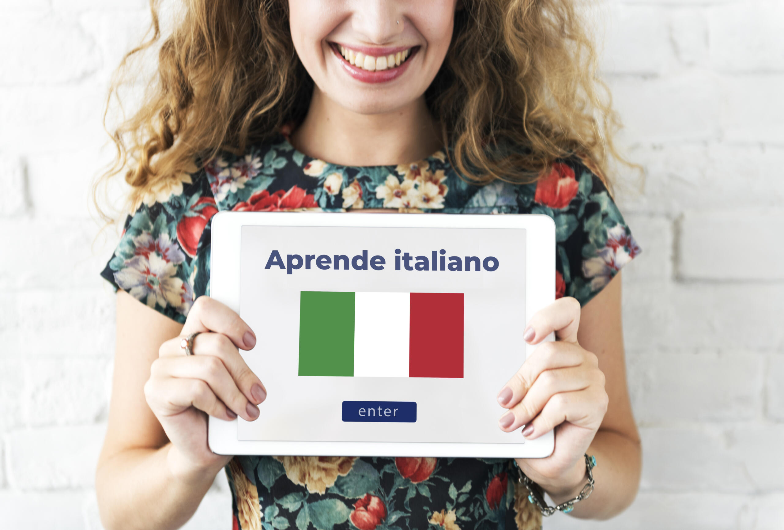 chica sonriente sosteniendo una tablet con el mensaje "Aprende italiano" junto a 