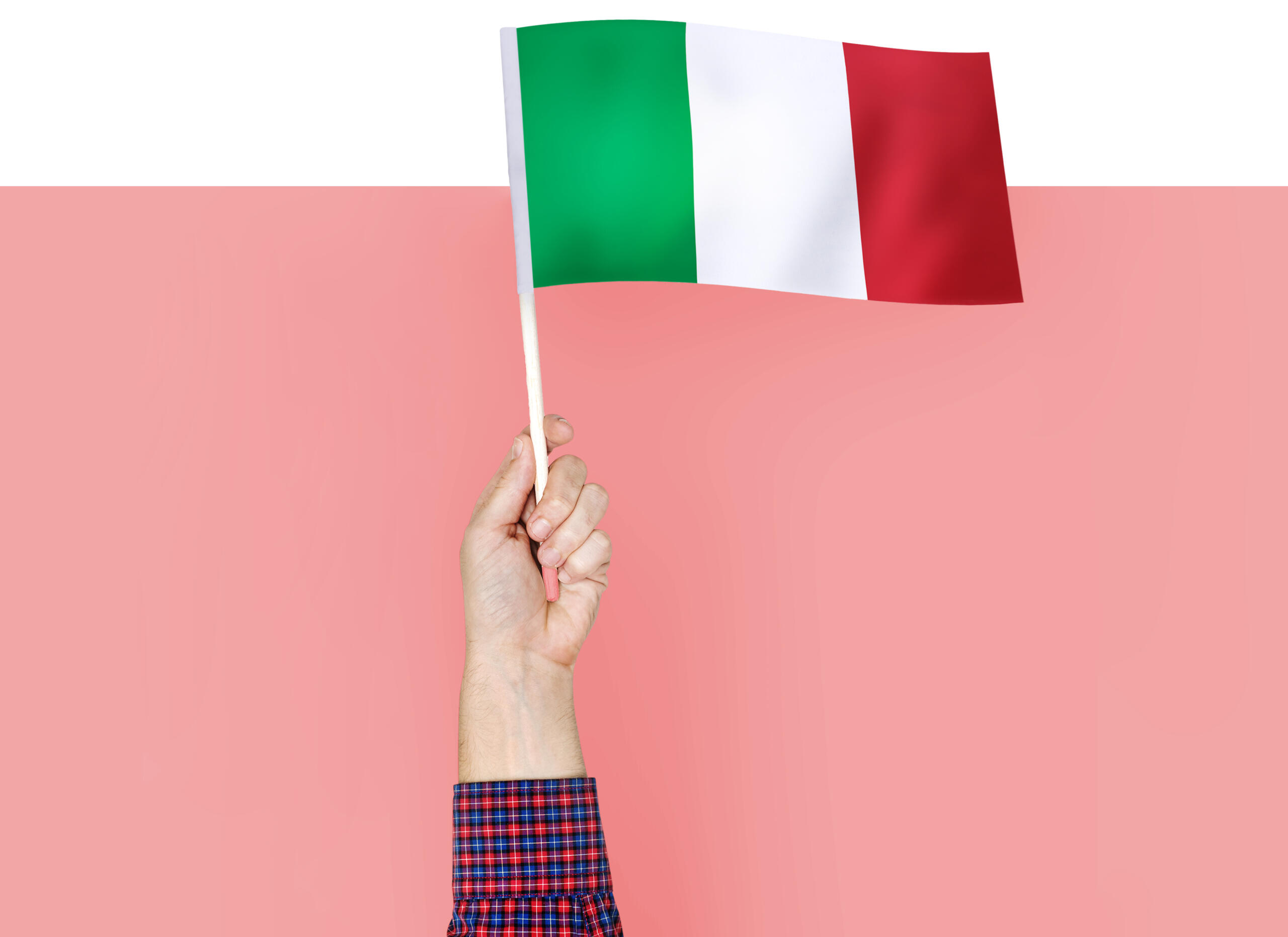 mano en fondo rosa sobresaliendo con un banderín de Italia