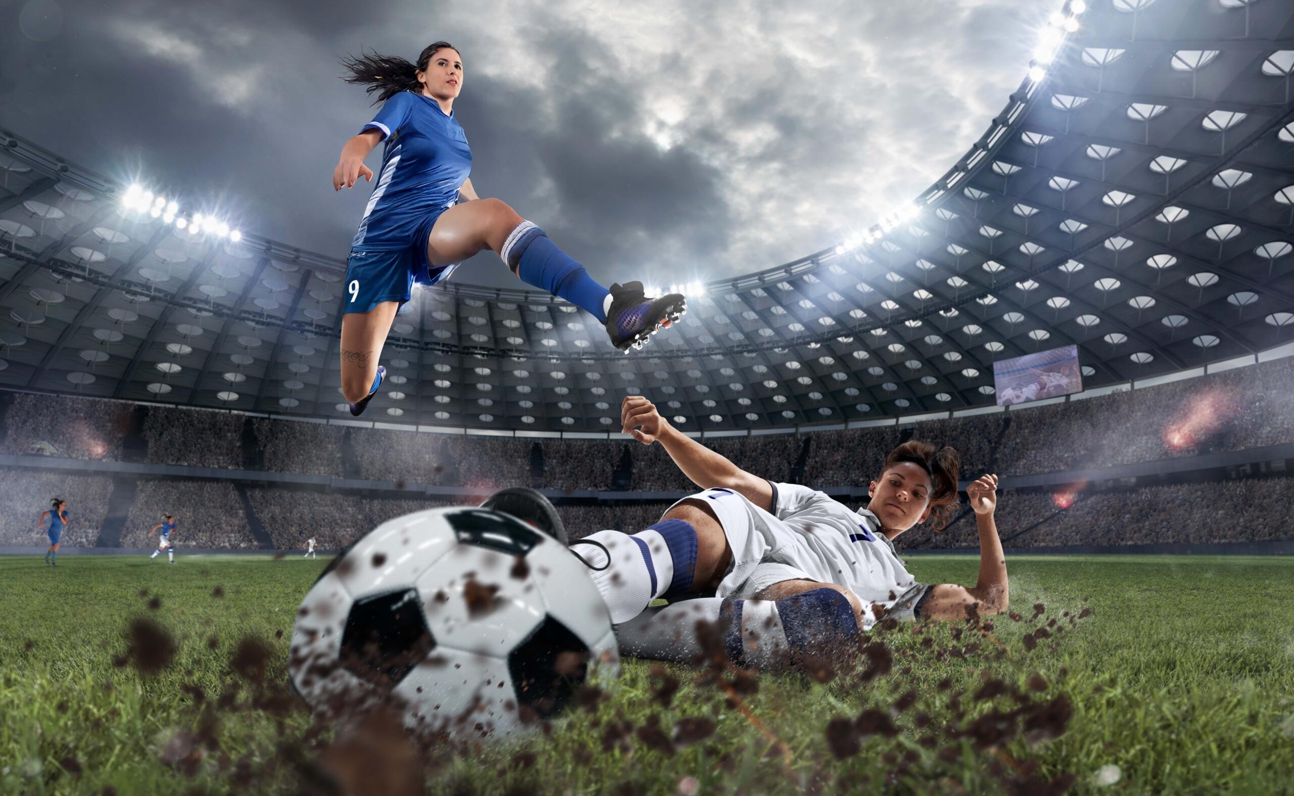 toma epica de dos jugadoras de fútbol barriéndose en la cancha por una pelota