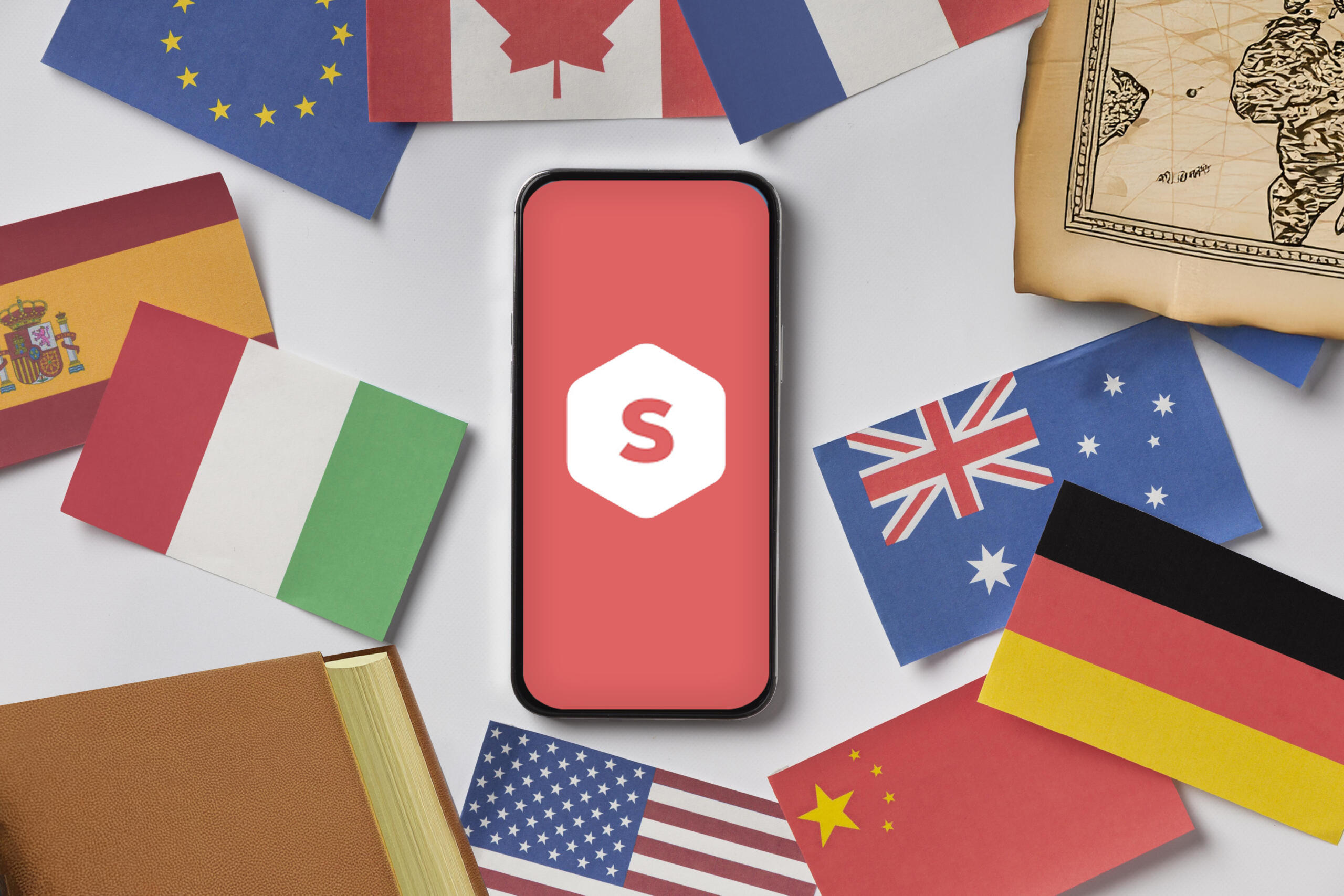 vista cenital de celular en la mesa con logo de superprof en medio y banderas dispersas alrededor de diferentes países