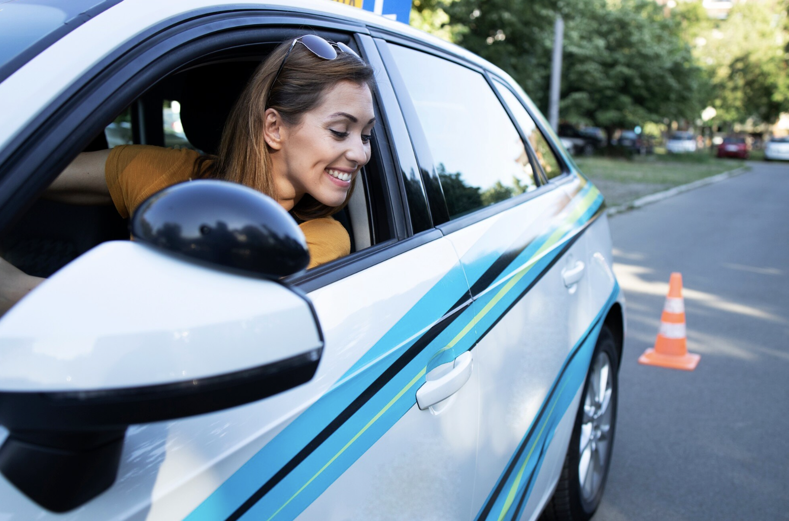 chica practicando para estacionarse mirando desde la ventana de conductor hacia abajo.