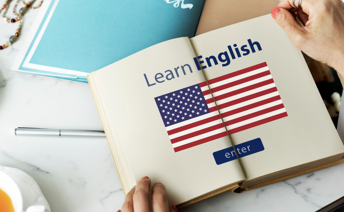 libro abierto con bandera de estados unidos y frase Learn English  sobre esta