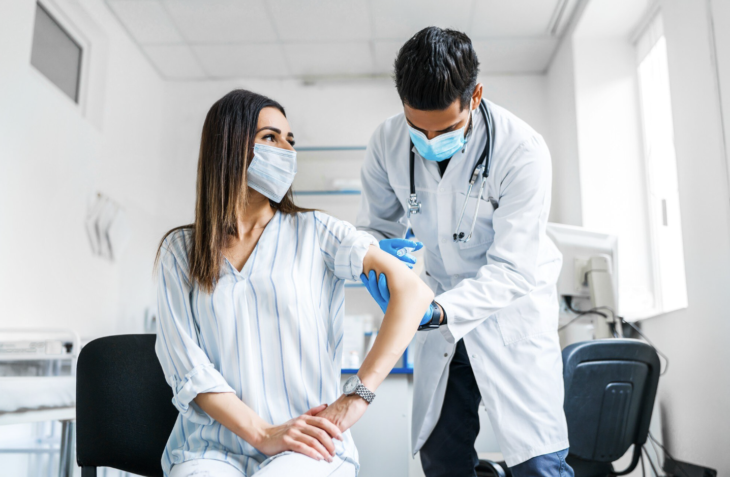 doctor en un consultorio colocando una inyección a una paciente mujer