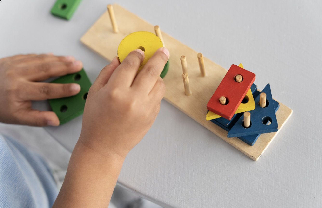 vista cenital de las manos de un niño armando torres con formas diversas en juguete montessori