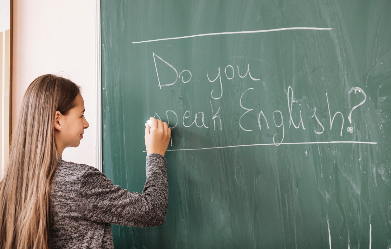 profesora escribiendo en pizarra verde Do you speak english?