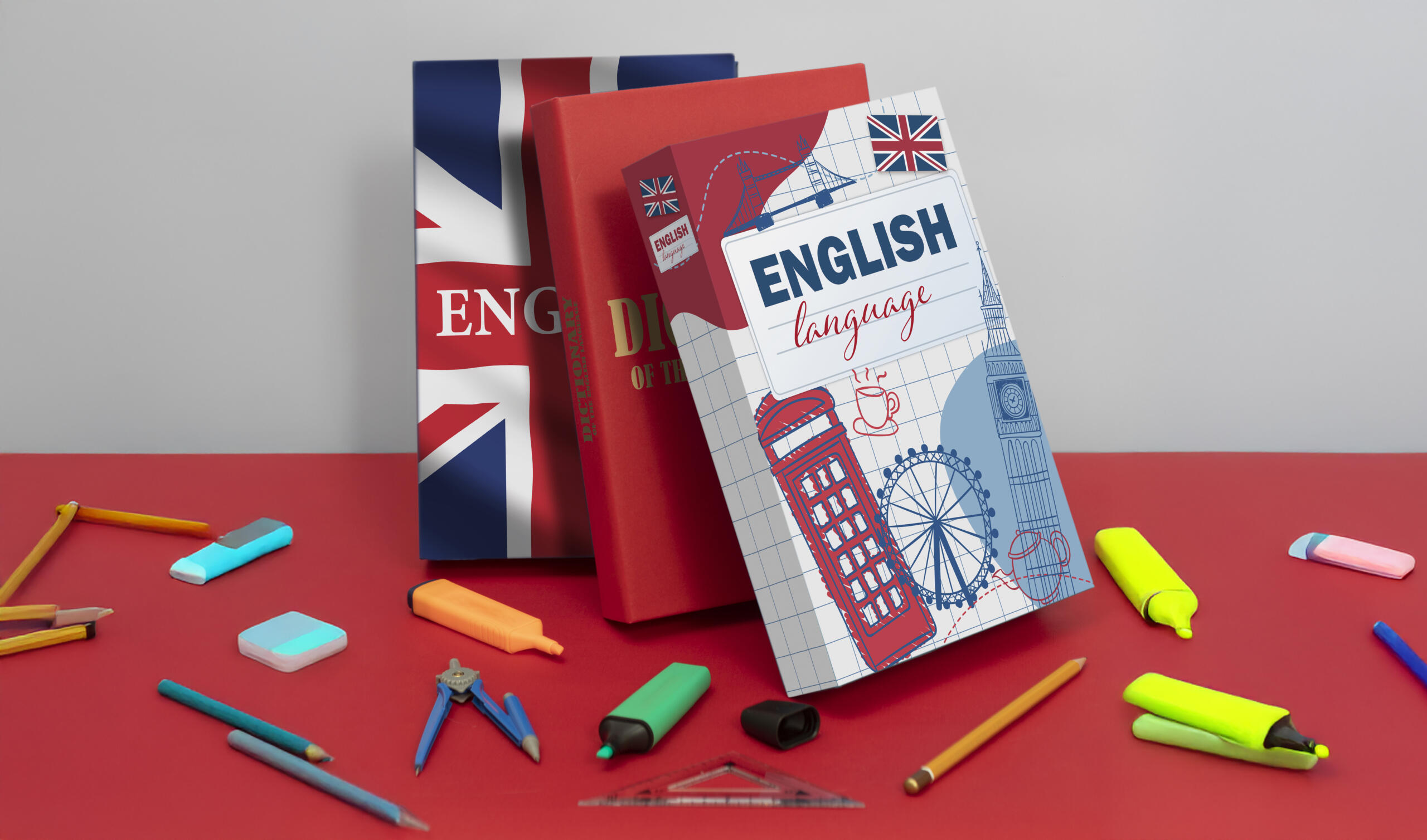 tres libros de inglés apilados verticalmente y utiles escolares dispersos sobre una mesa roja