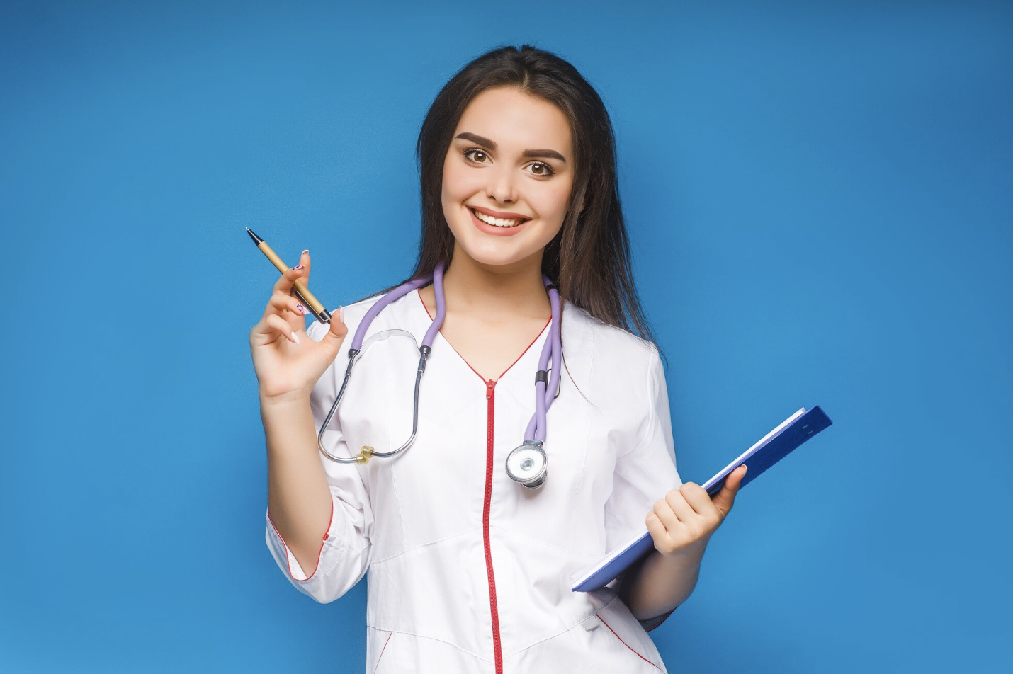 chica vestida con traje medico mirando sonriente a la camara con un estetoscopio en el cuello, un lapicero en la mano izquierda y un folder en la mano derecha