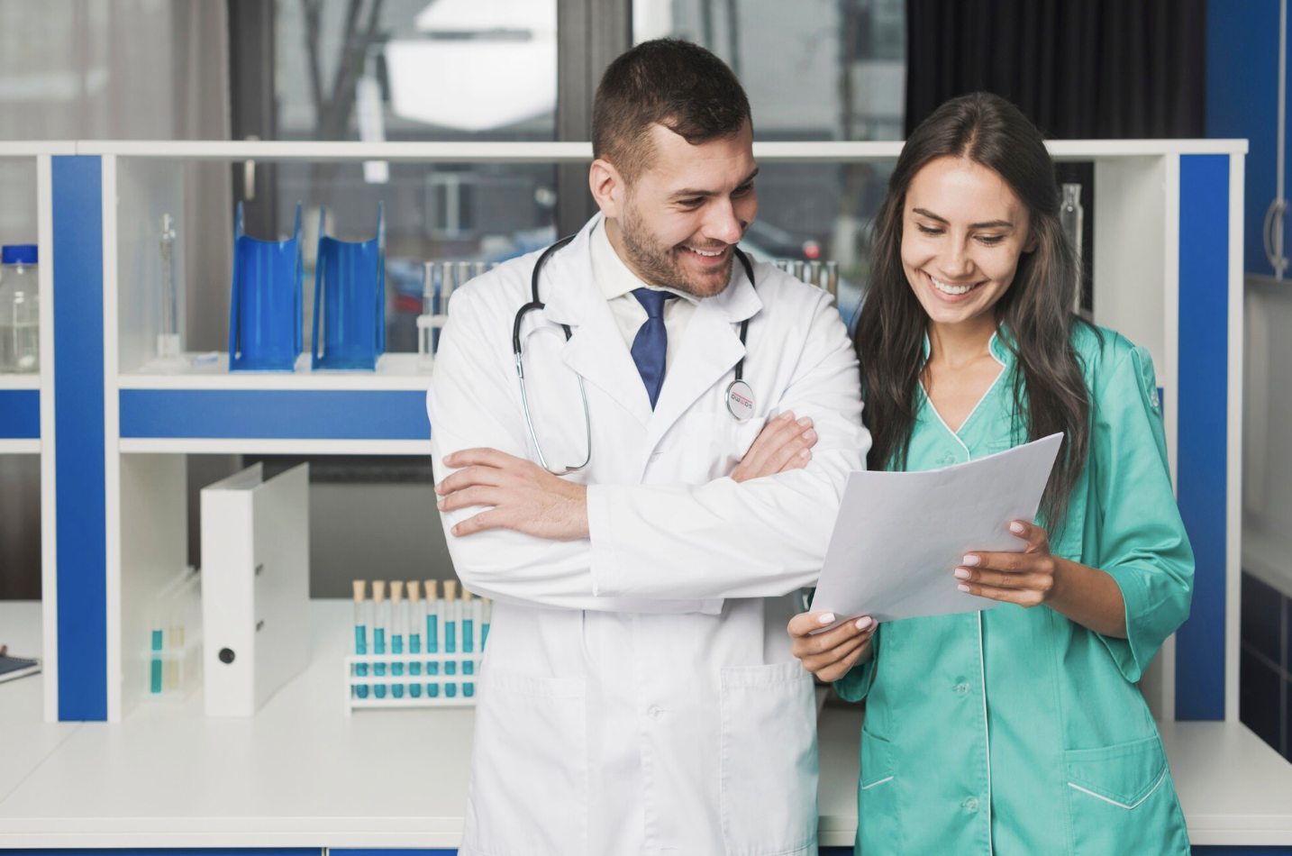 se ve a un doctor y a una enfermera revisando unos documentos sonrientes en medio de un consultorio