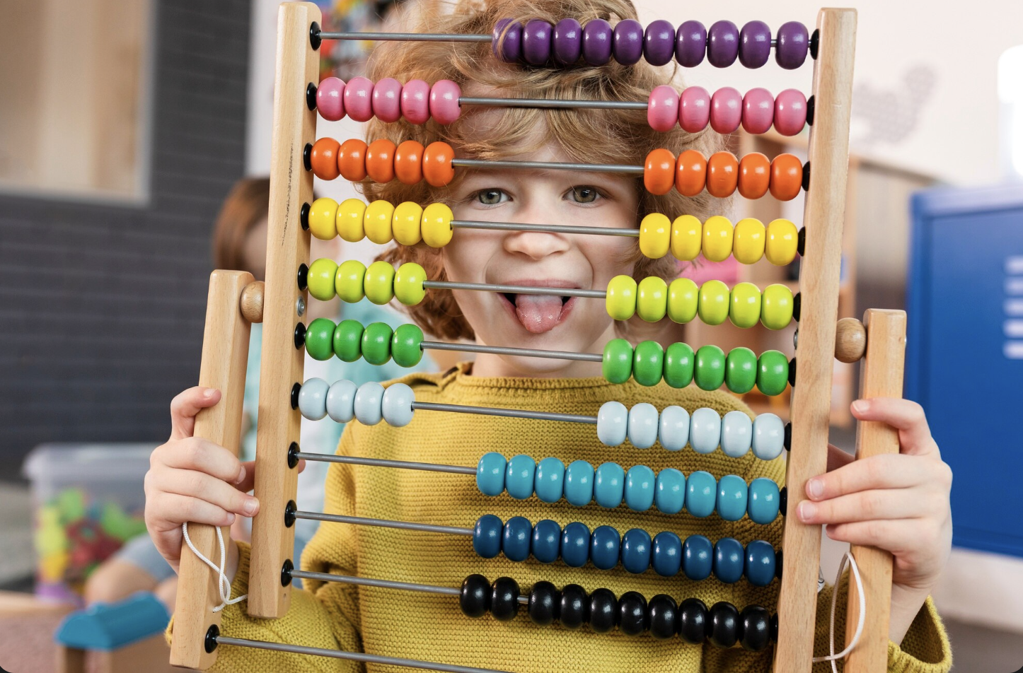 niño sonriente sacando la lengua a través de un ábaco con diferentes cuentas de colores
