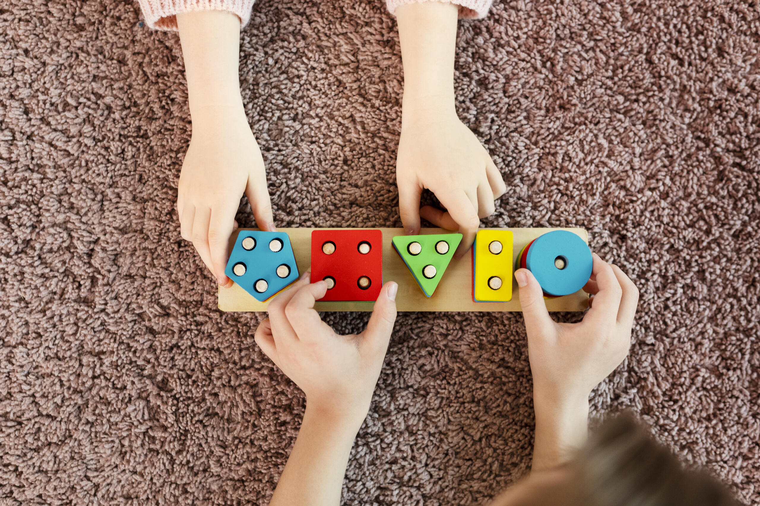 toma cenital de manos de niños jugando con una pila de formas de colores