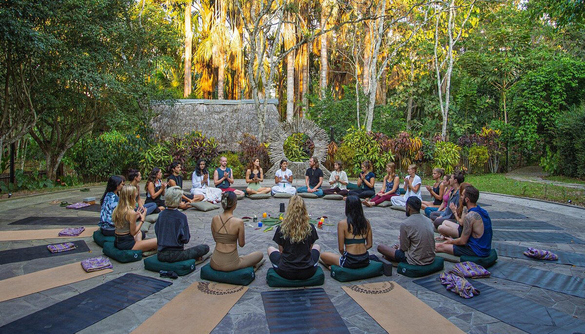 circulo de meditacion de un grupo de personas haciendo yoga en medio de la selva