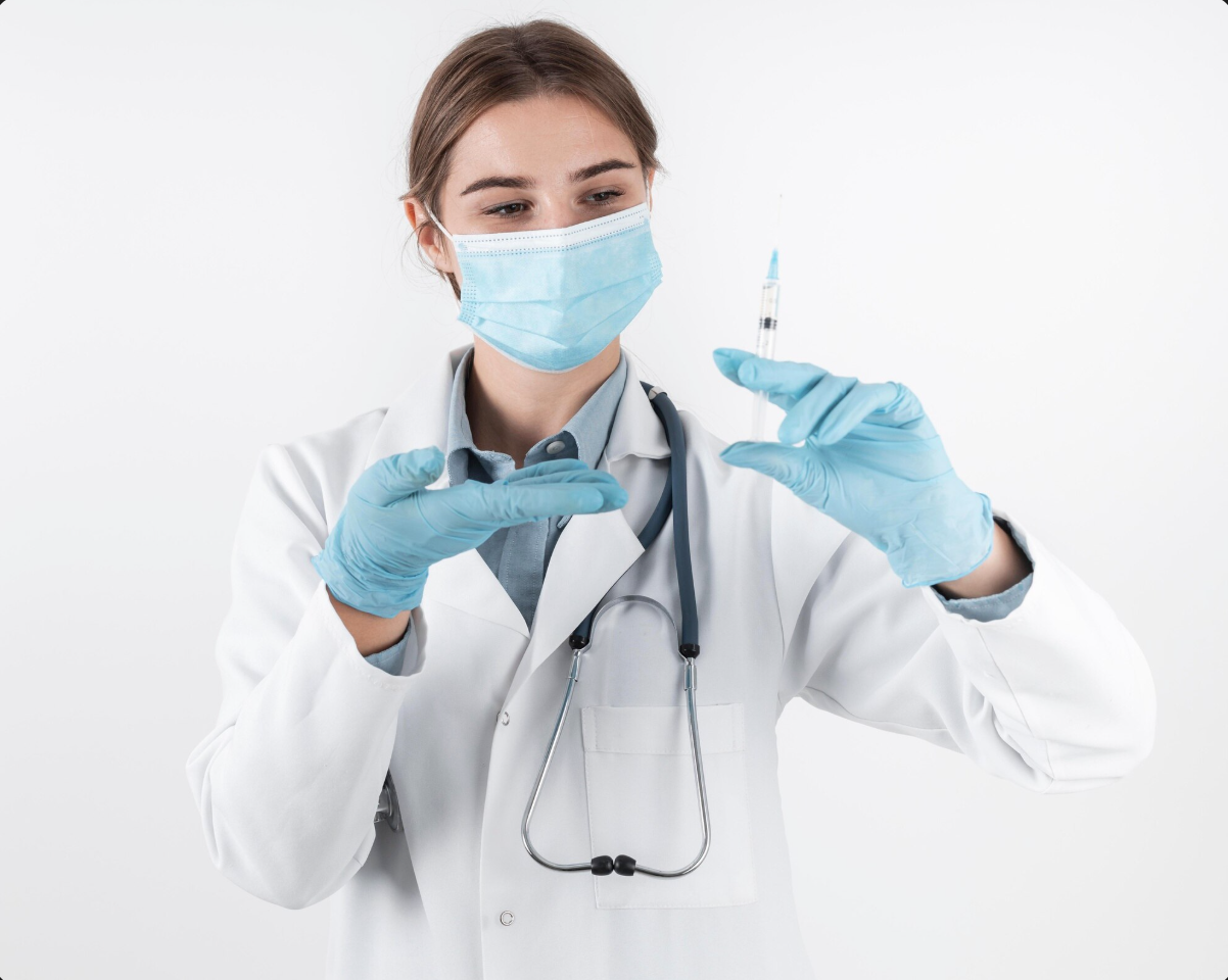 doctora con mascarilla y guantes quirurgicos mostrando una jeringa