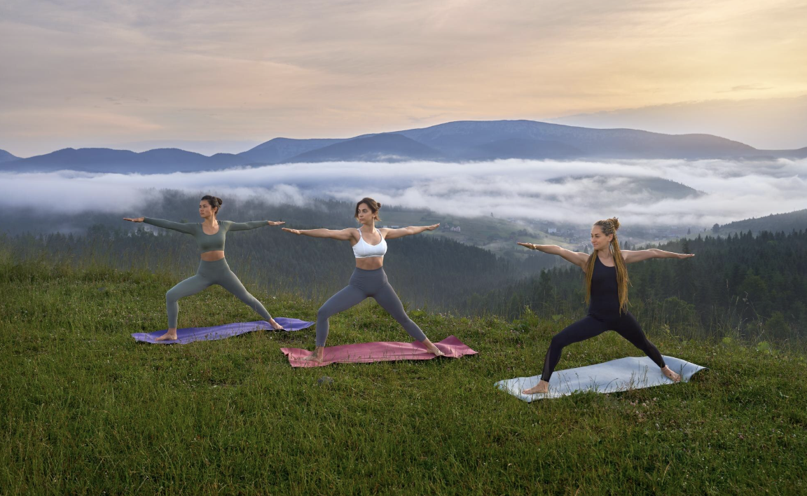 tres chicas haciendo yoga frente a las montañas