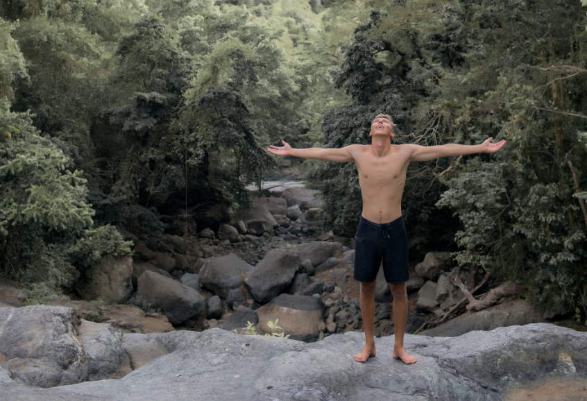 chico mirando al cielo con brazos extendidos mirando la naturaleza