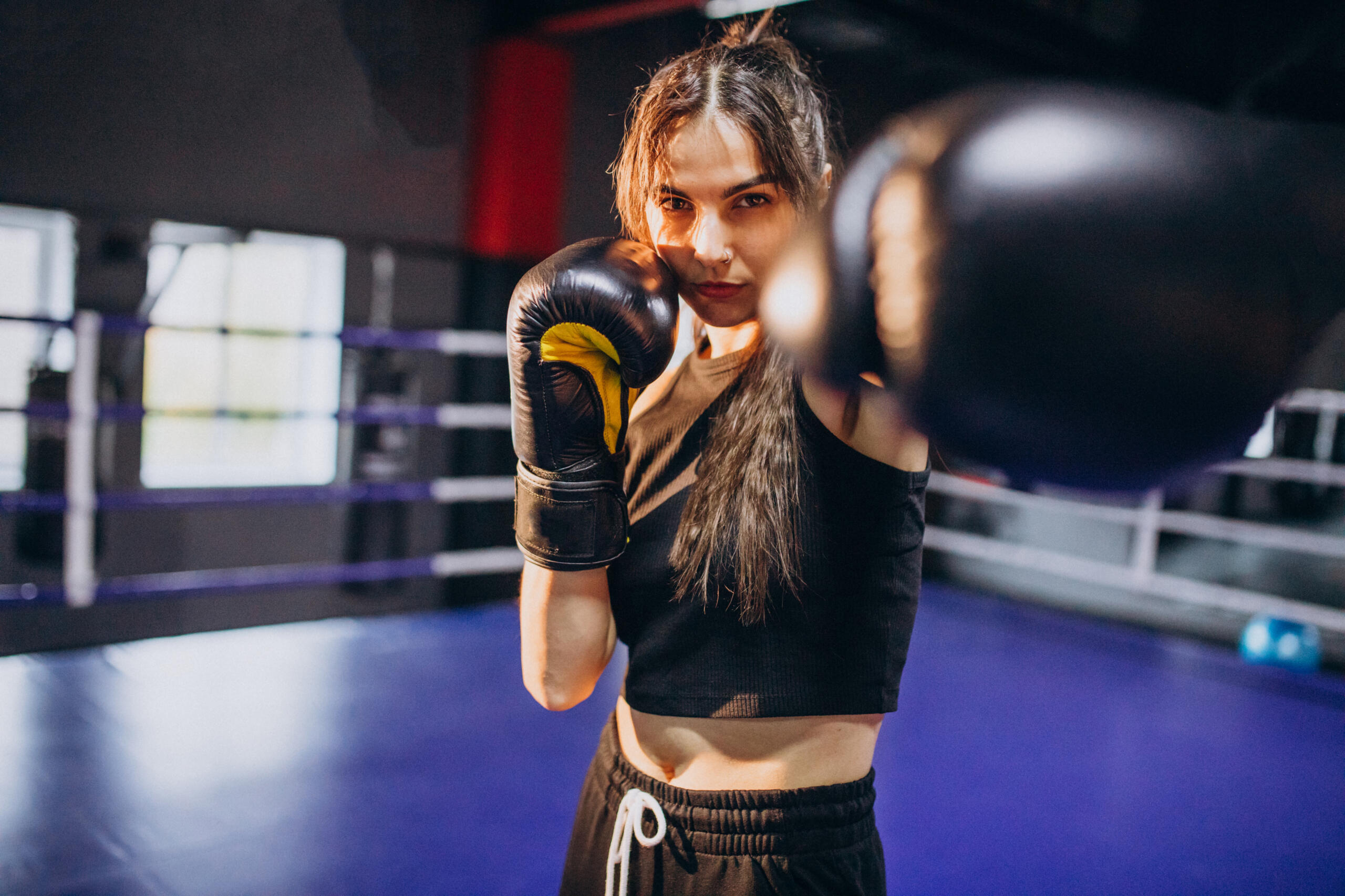 chica con guantes de box en el ring colocando un guante hacia la cámara