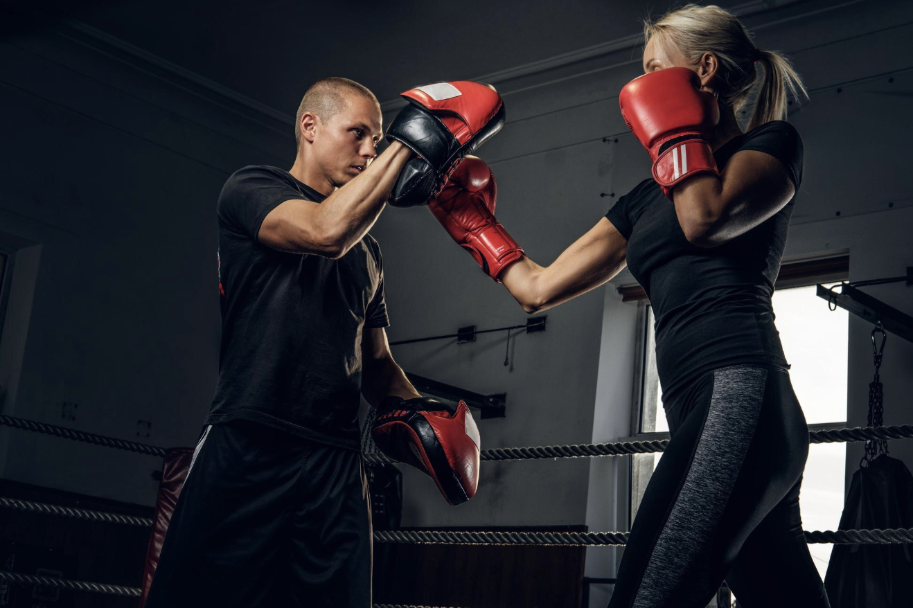 un profesor y su alumna de boxeo en un entrenamiento 