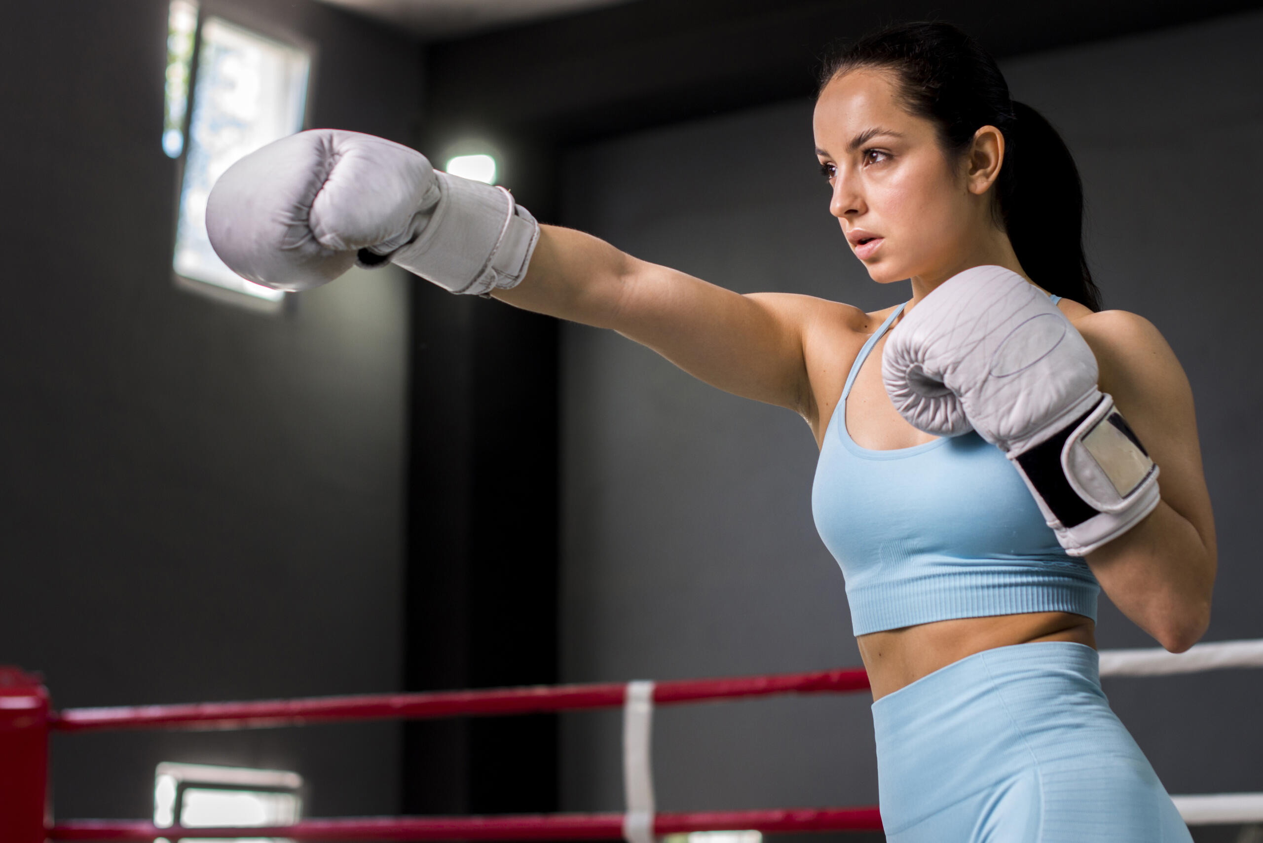 chica estirando un puño con guante en gym