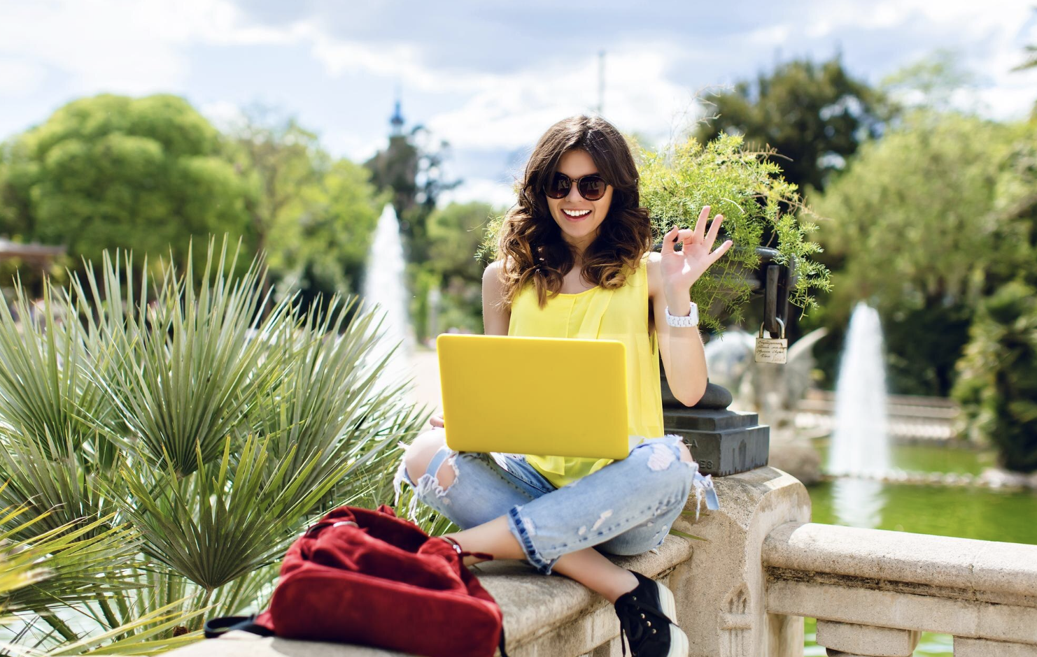chica sonriente con lentes de sol estudiando en campus de su universidad