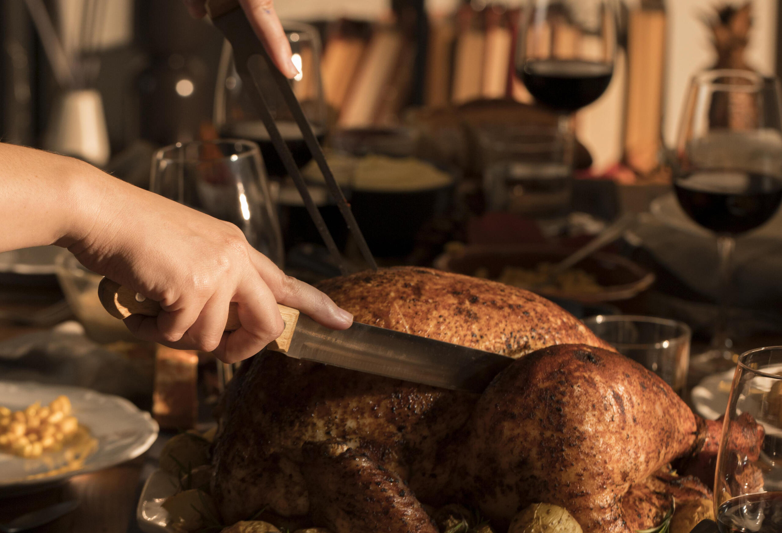 toma de lado viendo manos cortando pedazos de un pavo entero 