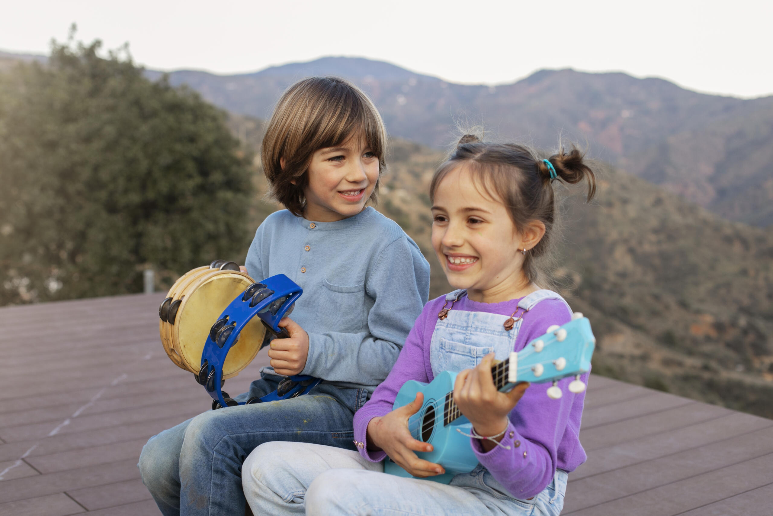 dos niños sonrientes sentados con panderetas y guitarra de juguete