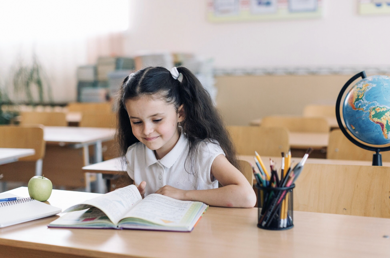 niña leyendo en un pupitre del salon de clases