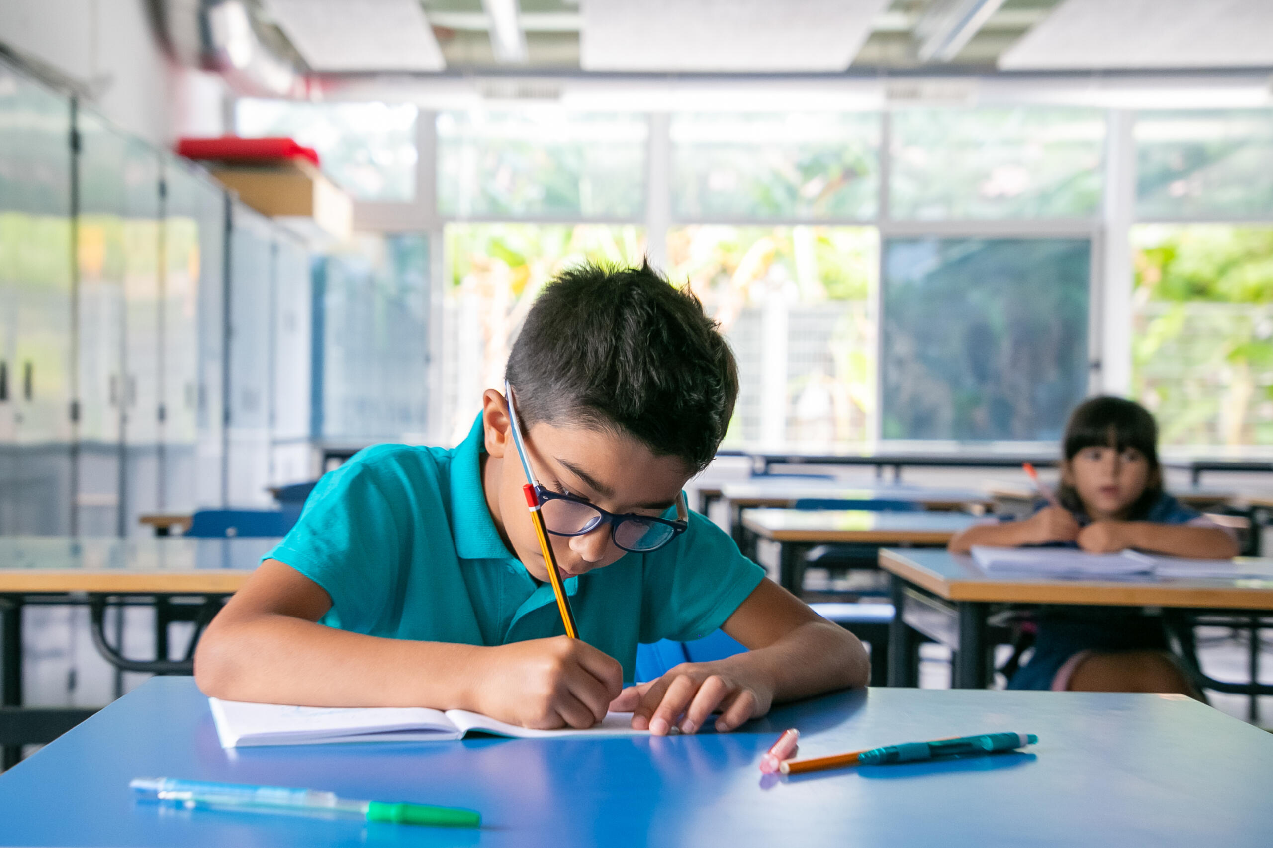 niño en carpeta de aula concentrado escribiendo en su cuaderno