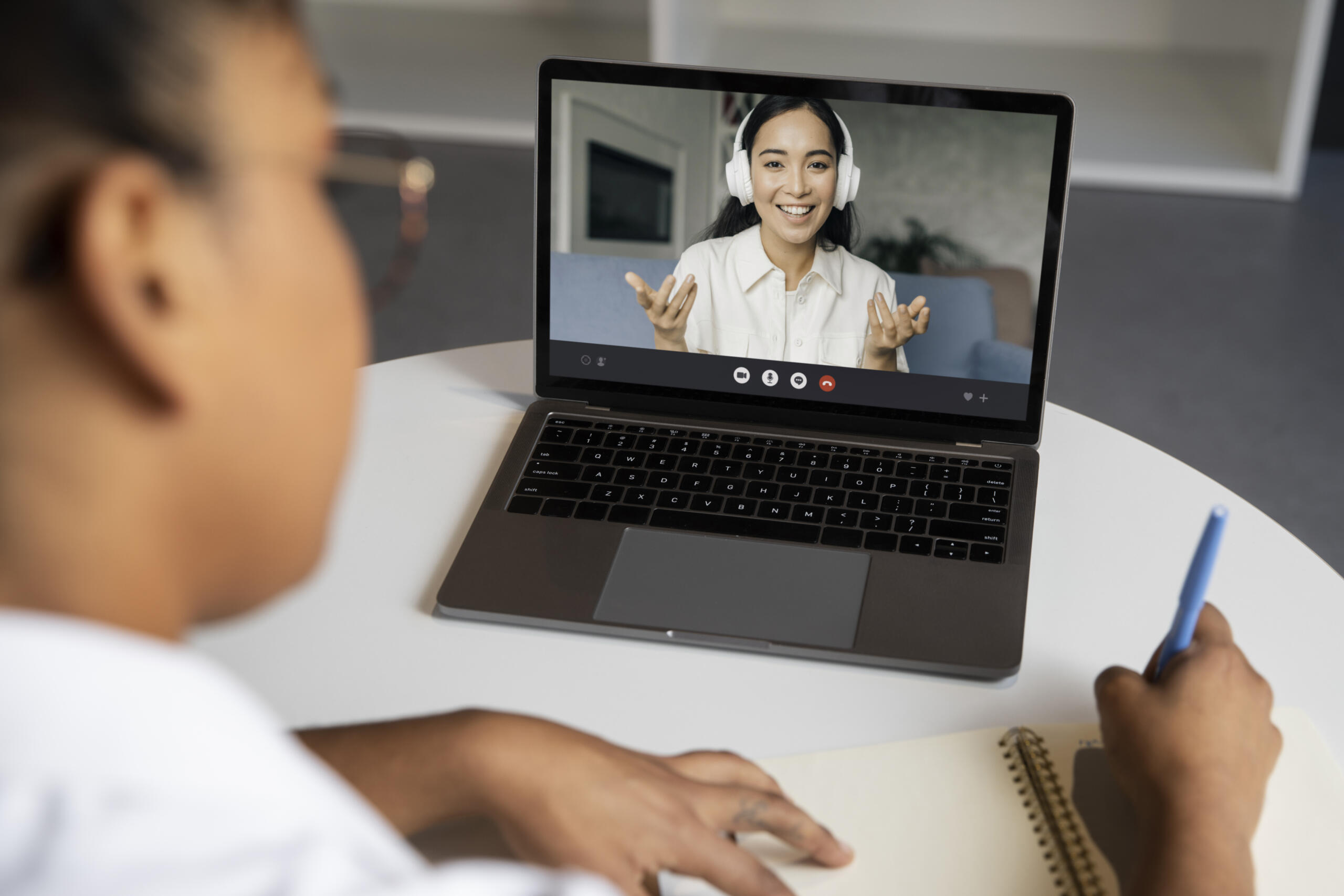 vista desenfocada de una alumna estudiando y laptop donde se ve a la profesora en videollamada en primer plano