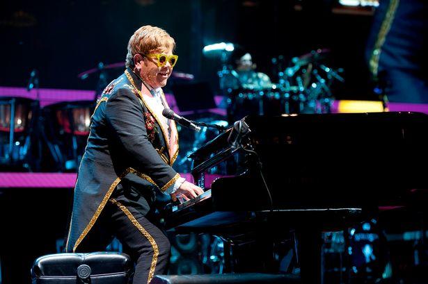 Elton John grający na pianinie na stojąco