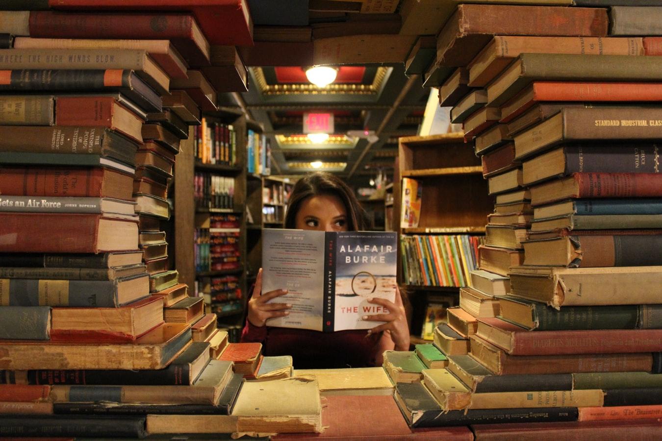 dziewczyna siedząca w bibliotece pomiędzy książkami