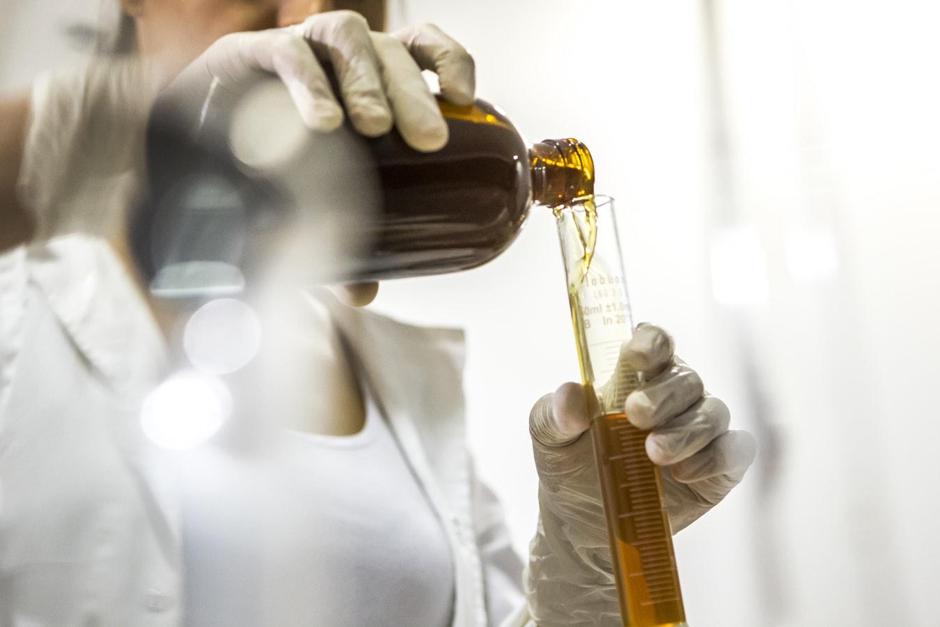 naukowiec przelewający związki chemiczne do probówek