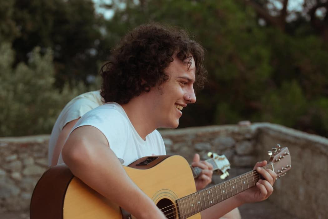 Chłopak z kolczykiem w nosie grający na gitarze