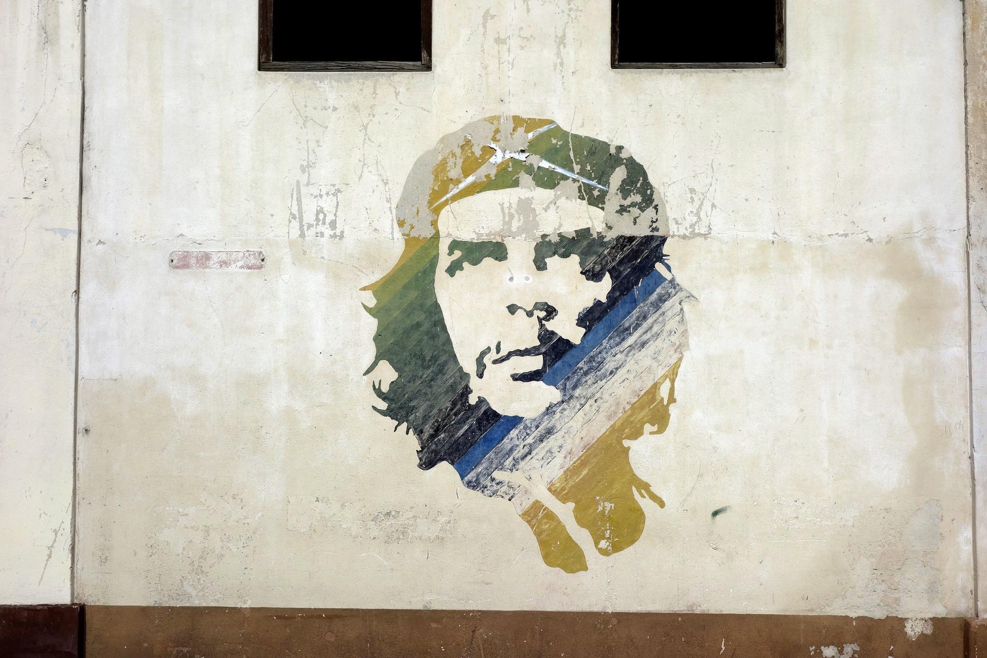 Kolorowy mural z wizerunkiem Che Gueavry na białej ścianie.