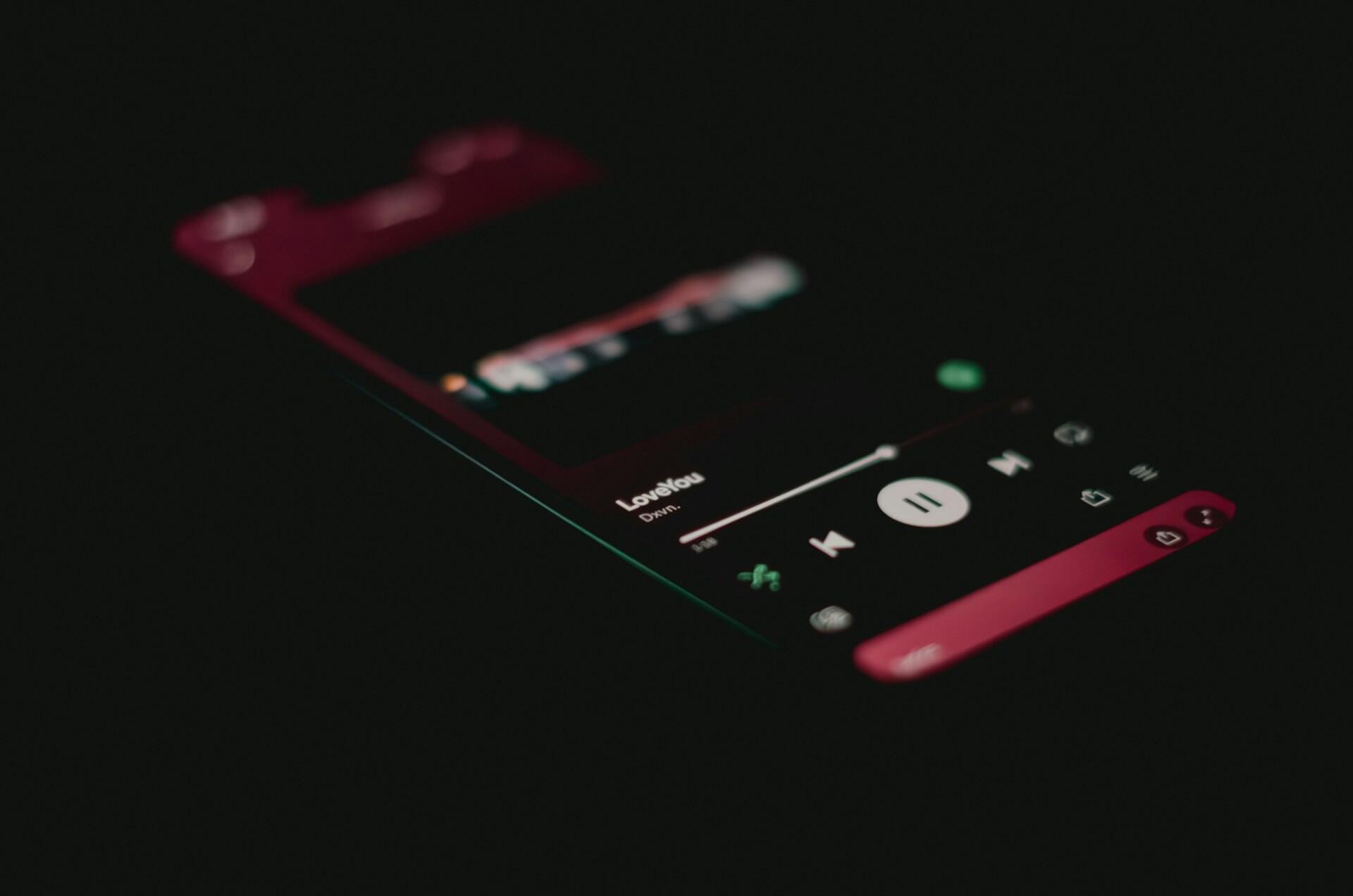 Zbliżenie na smartfon, na którym wyświetla się odtwarzacz muzyczny z odtwarzanym utworem „Lovely” w wykonaniu Billie Eilish i Khalida.