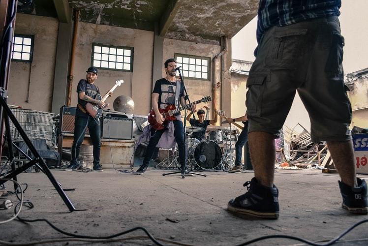 Czwórka mężczyzn grająca na gitarach i perkusji