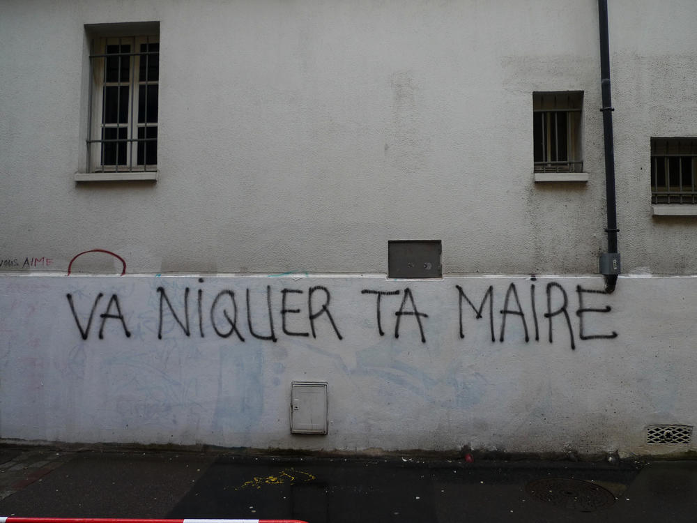 Slang francuski napisany na białej ścianie, graffiti, okna.