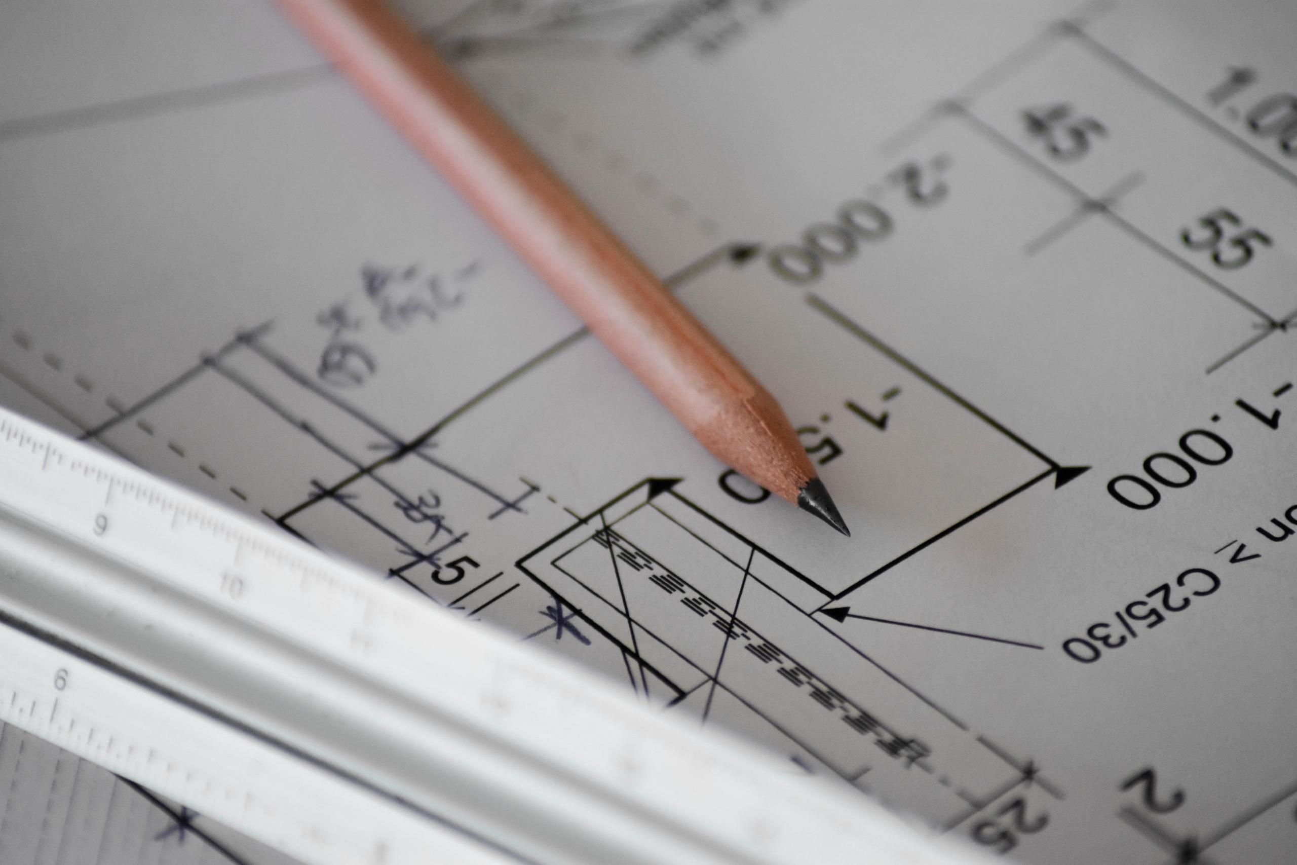 Ołówek i linijka leżące na projekcie architektonicznym.