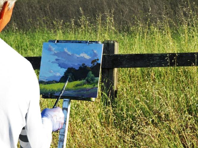 mężczyzna malujący obraz natury na płótnie
