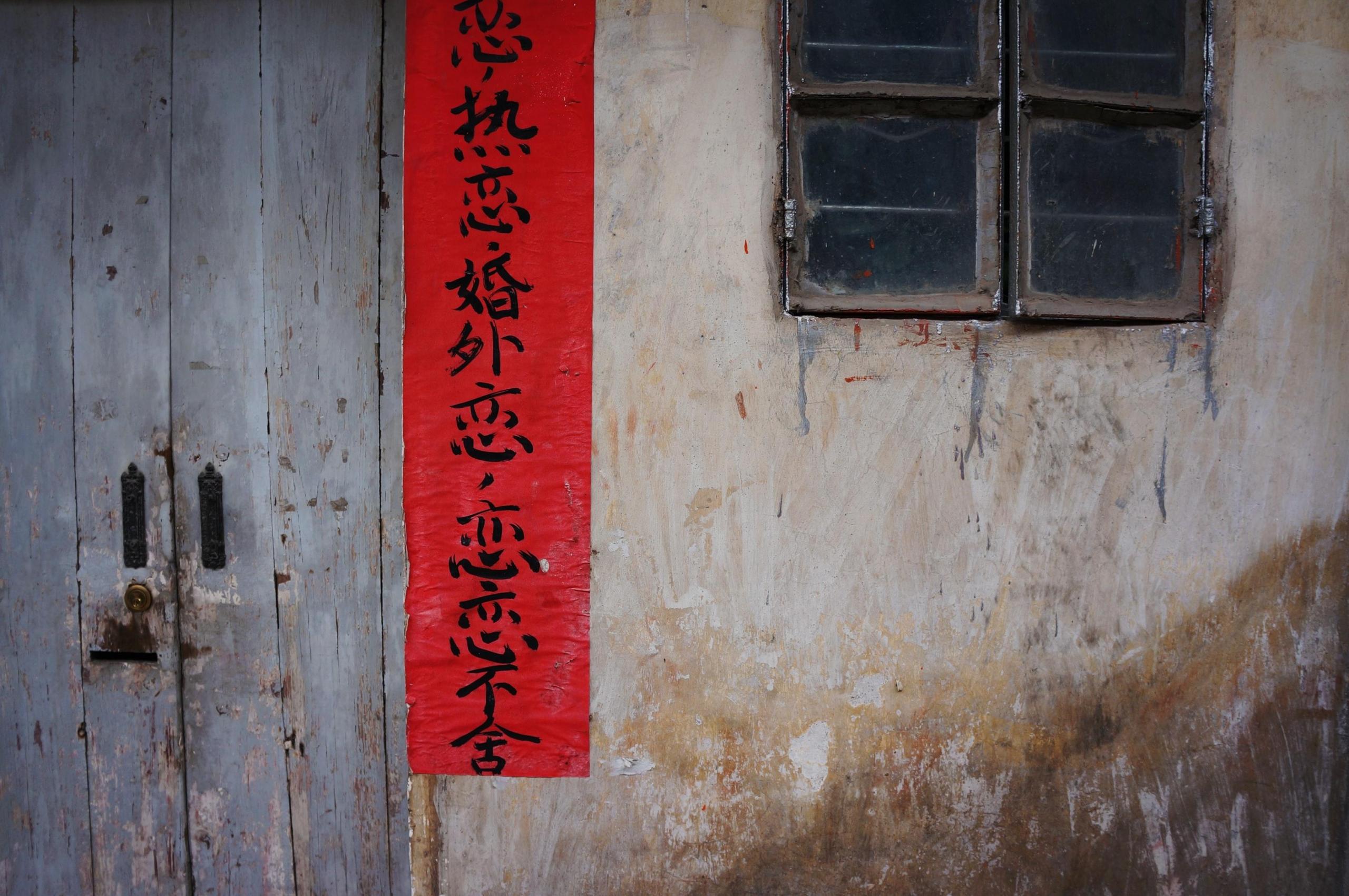 szarfa z chińskimi znakami zawieszona na ścianie starego domu